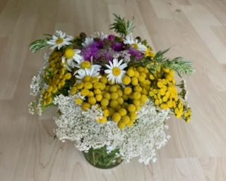 Foto eines Blumenstraußes zum Tag der Einfachheit: am Wegesrand selbst gepflückt und in ein leeres Schraubglas gestellt.